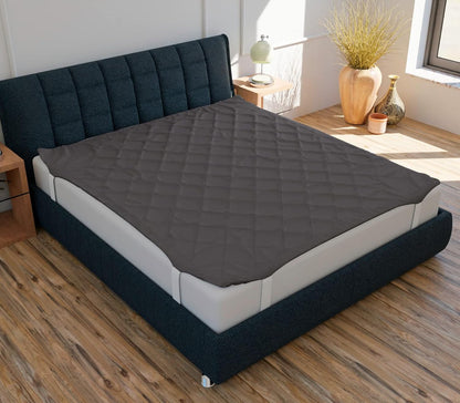 A navy blue mattress protector on a queen-sized bed with a textured surface, displayed in a room setting with decorative elements around.